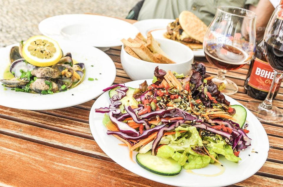 Fresh salad with colorful vegetables, steamed baby clams in garlic, hamburger 