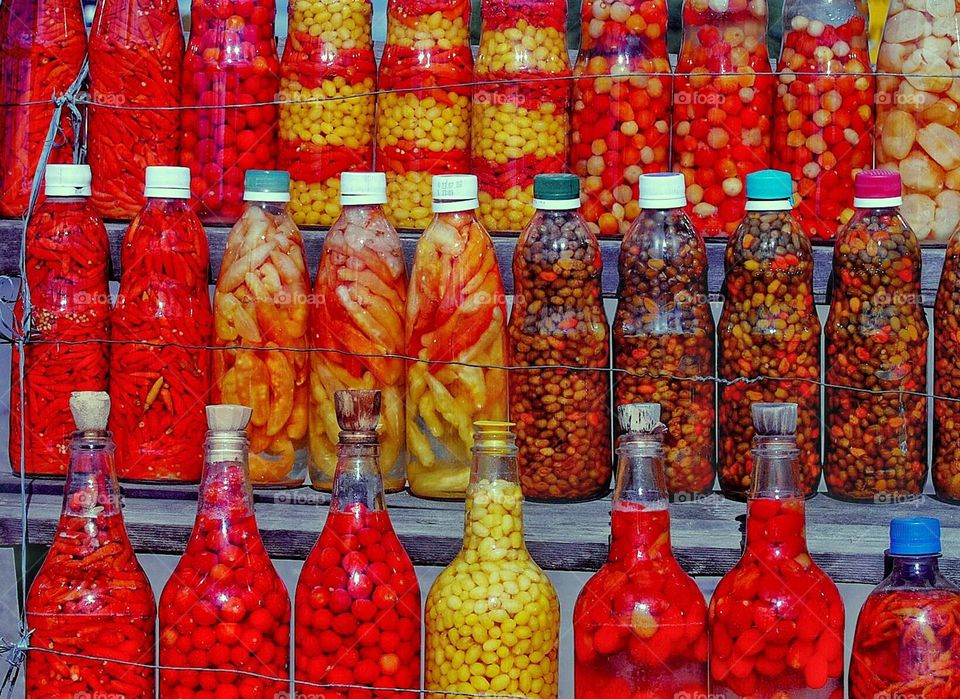 several glass bottles with colored peppers