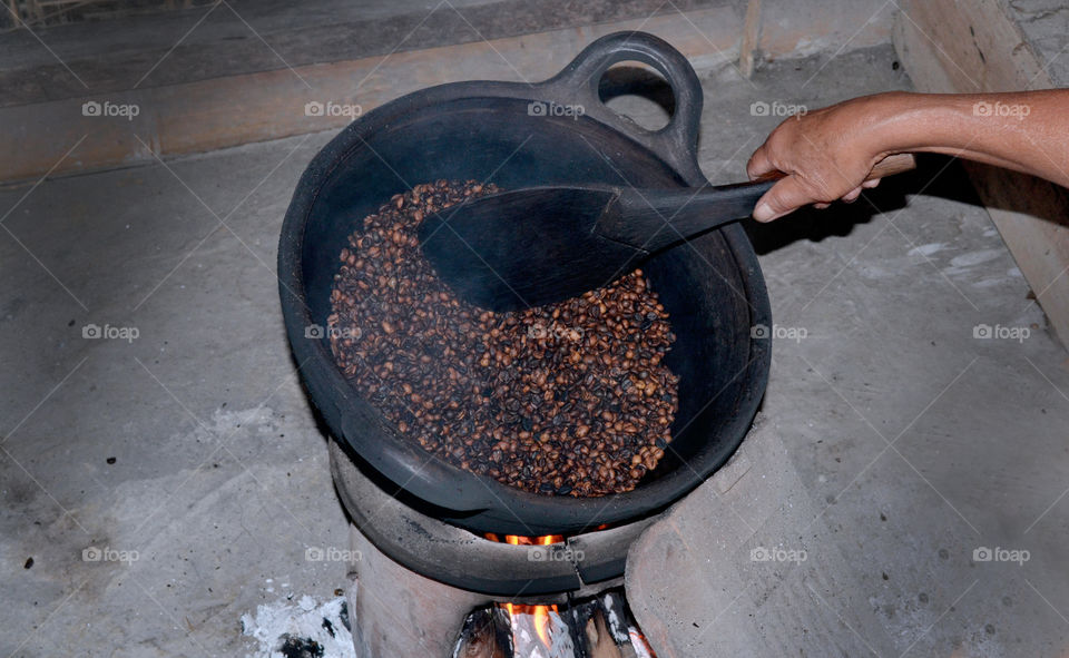 Traditional process of frying coffee beans using a stove.