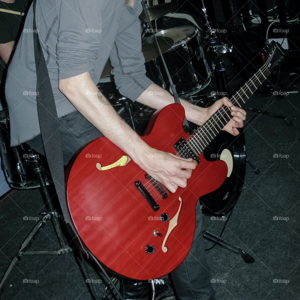 A man playing a red guitar