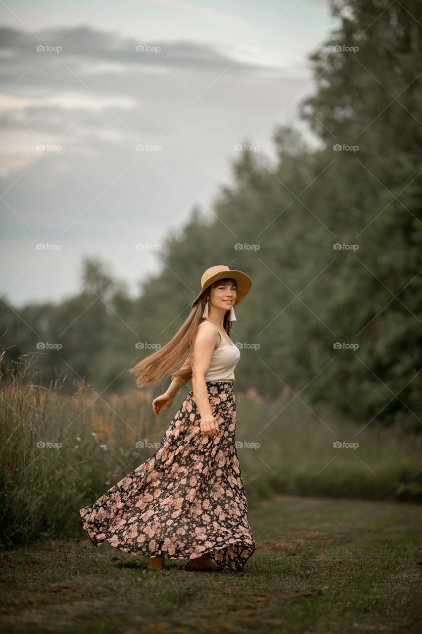 Beautiful young woman in a field of blossom flowers in boho style