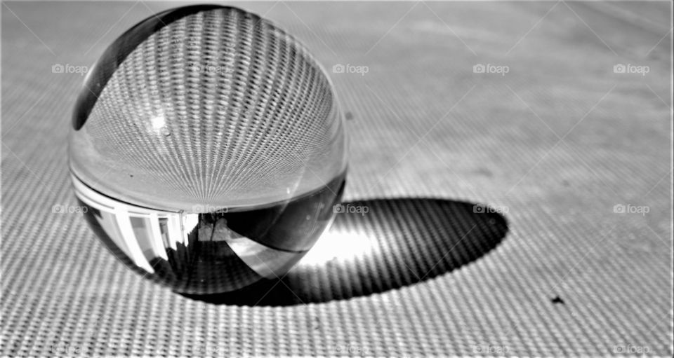 Crystal clear glass ball on a relief concrete surface in black and white