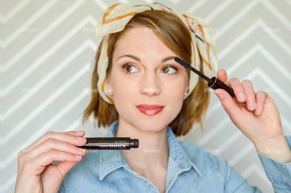 Woman applying AVON Super Shock mascara to eyelashes