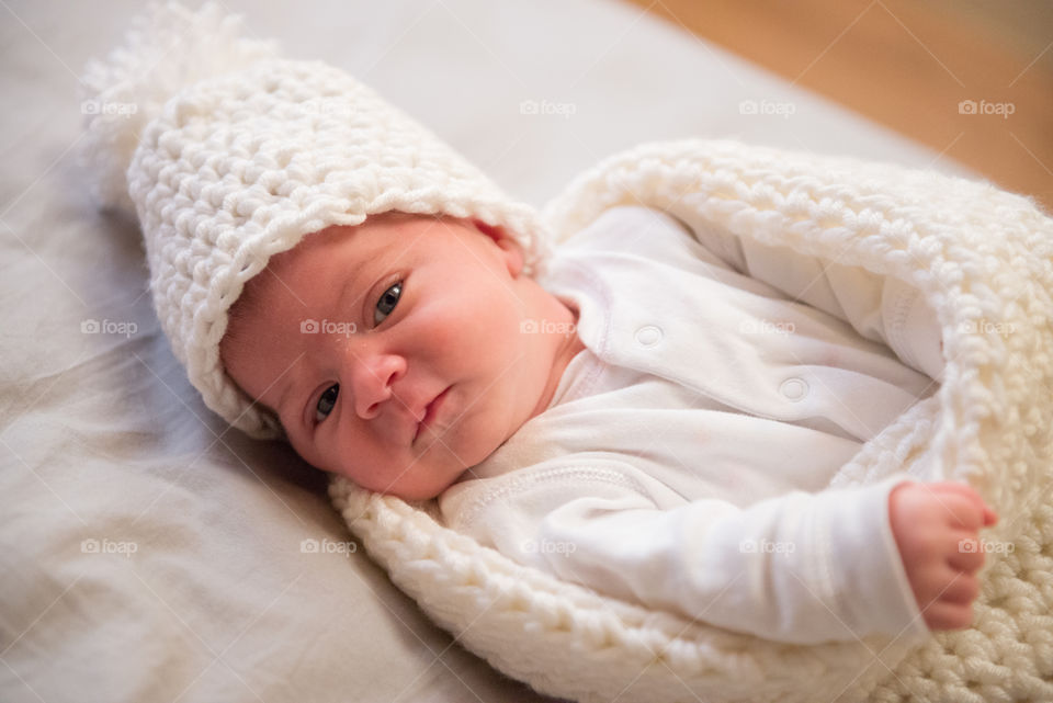 newborn in a crochet hat and cocoon