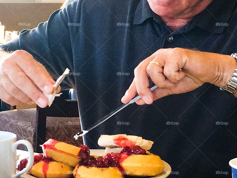 Man eating breakfast of strawberry waffles with whipped cream