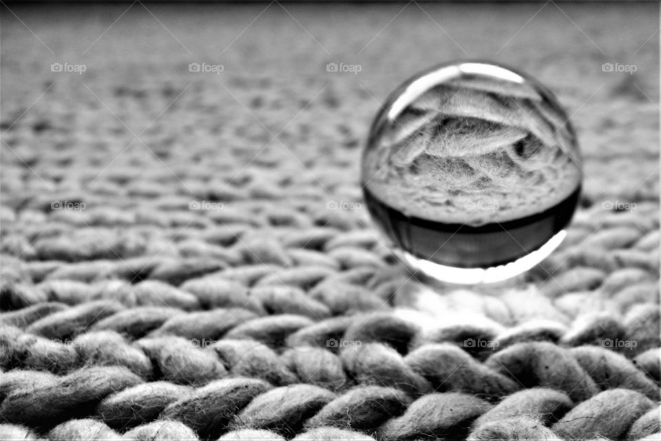 Crystal clear glass ball on knitted carpet in black and white abstract picture