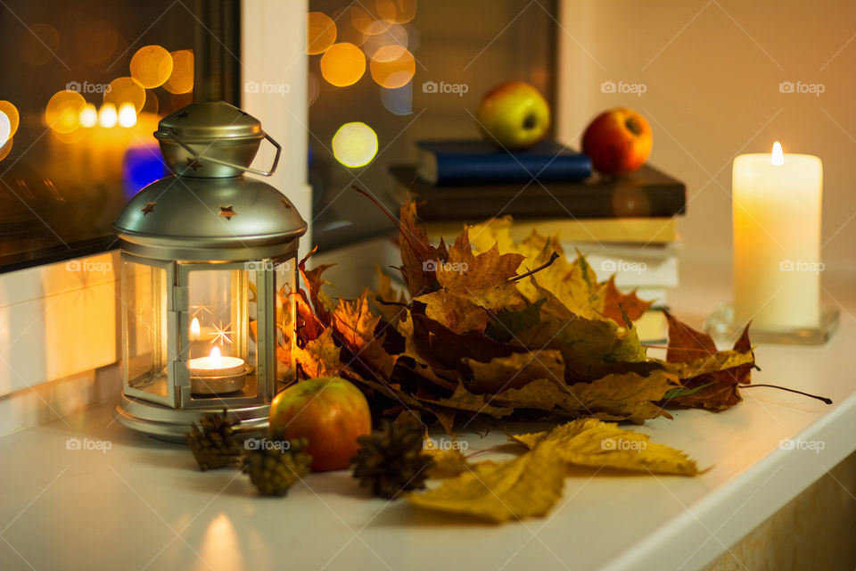 Still life with autumn leaves, candles, books on the windowsill