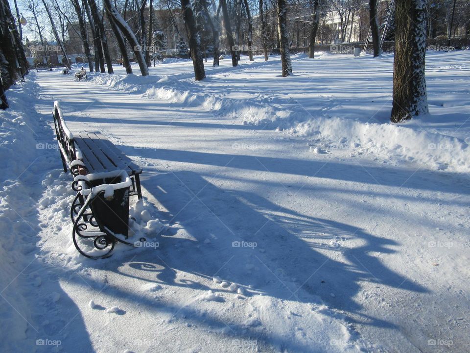 sunny winter day in the city, walk in the city park, benches in the snow