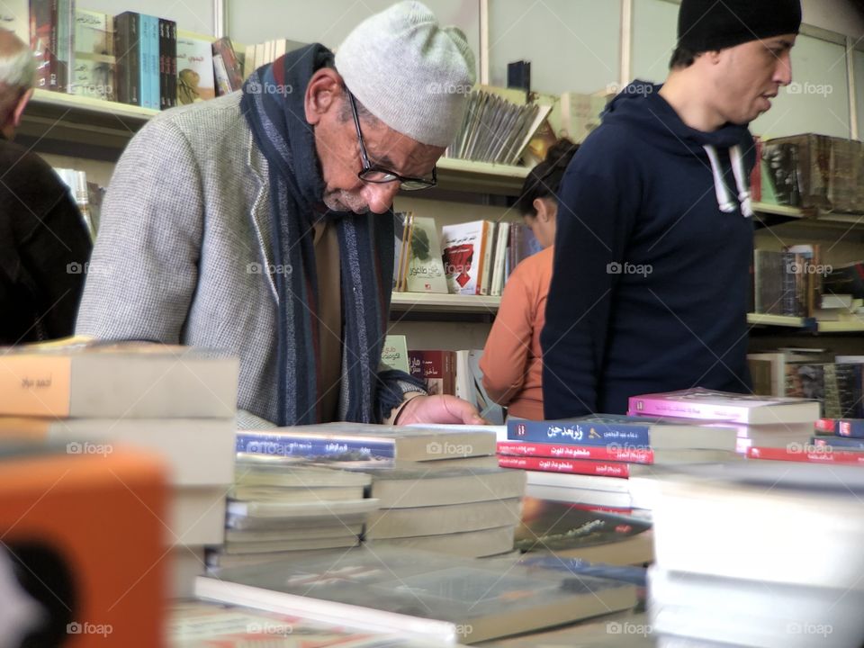 an old man searching for a book in the international book fair in egypt 2018