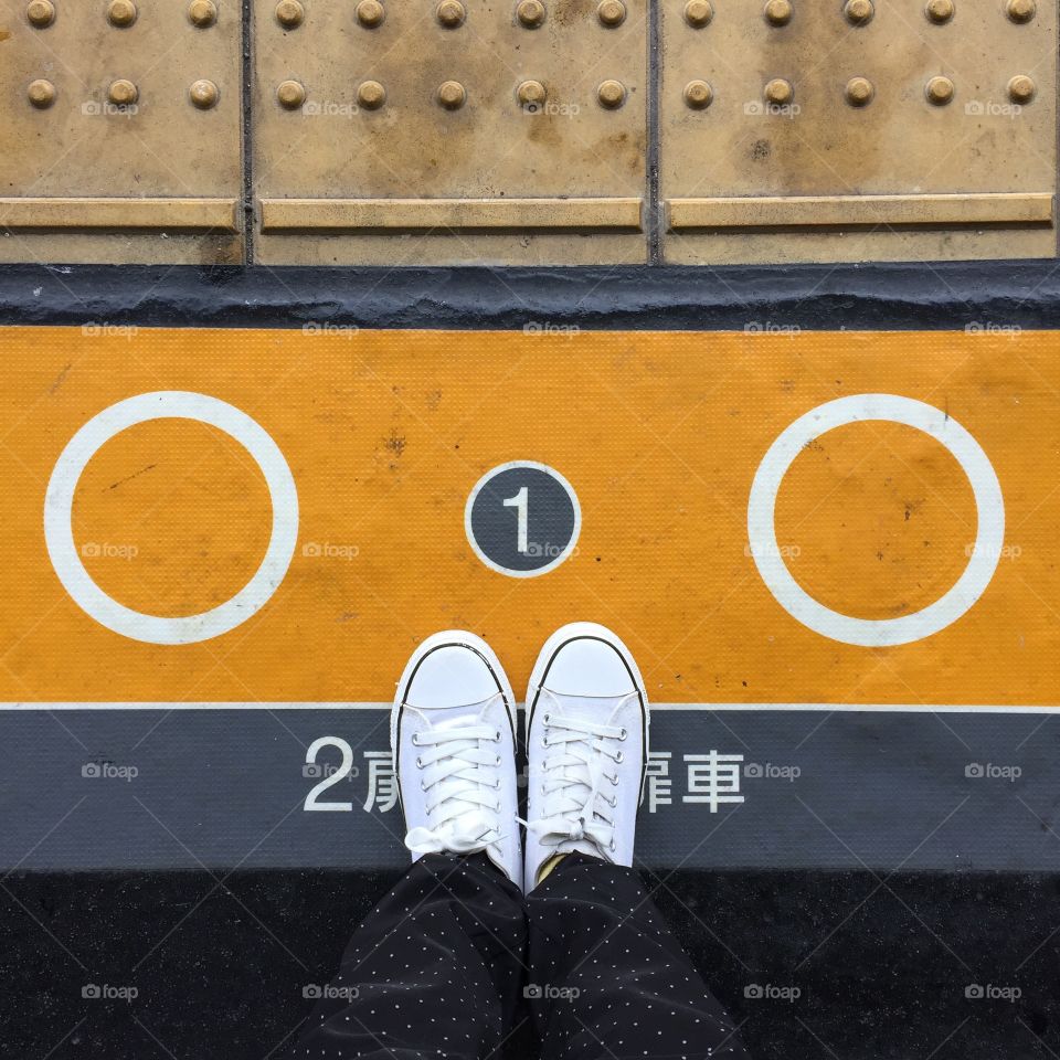 Close-up Picture of Woman Who Crossed Her Legs. Woman in Black Jeans and Sneakers Enjoying Daytime