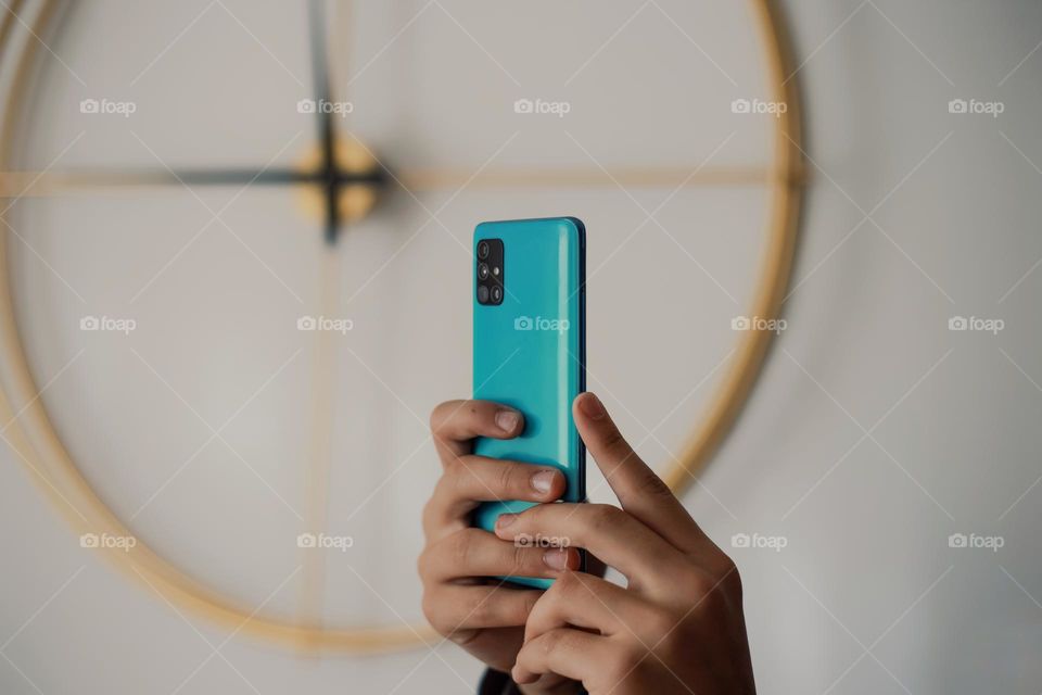 Close-up of hands holding smartphone against white background.