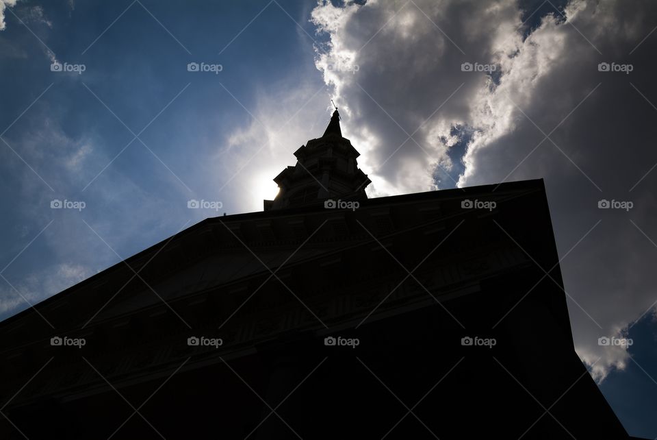 A church located in the historic downtown Savannah district sits in perfect silhouette behind the suns light at high noon.