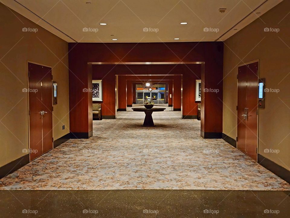 A long hotel hallway enhanced by hardwood and spot lighting creates a aesthetically pleasing atmosphere