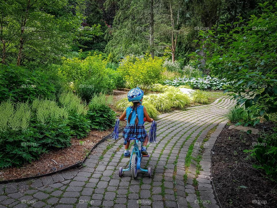 Cute little girl is riding her bicycle in the park