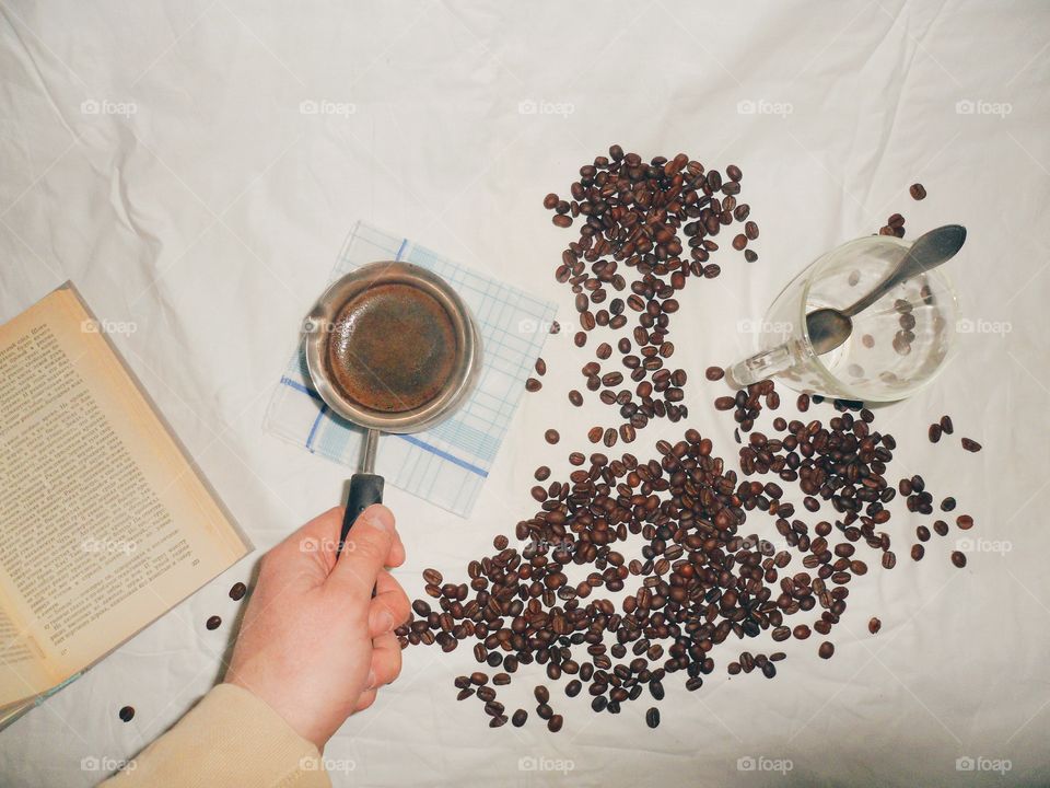 Turka for brewing coffee, a book, a cup with a spoon and coffee beans