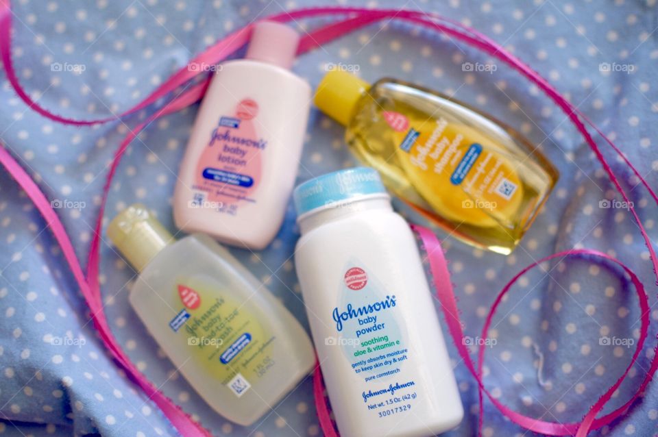 Johnson and Johnson baby products on a blue and white polkadot background with a pink ribbon flat lay