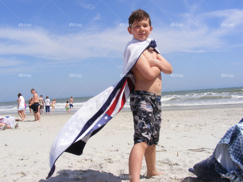 Shirtless boy standing on sandy beach