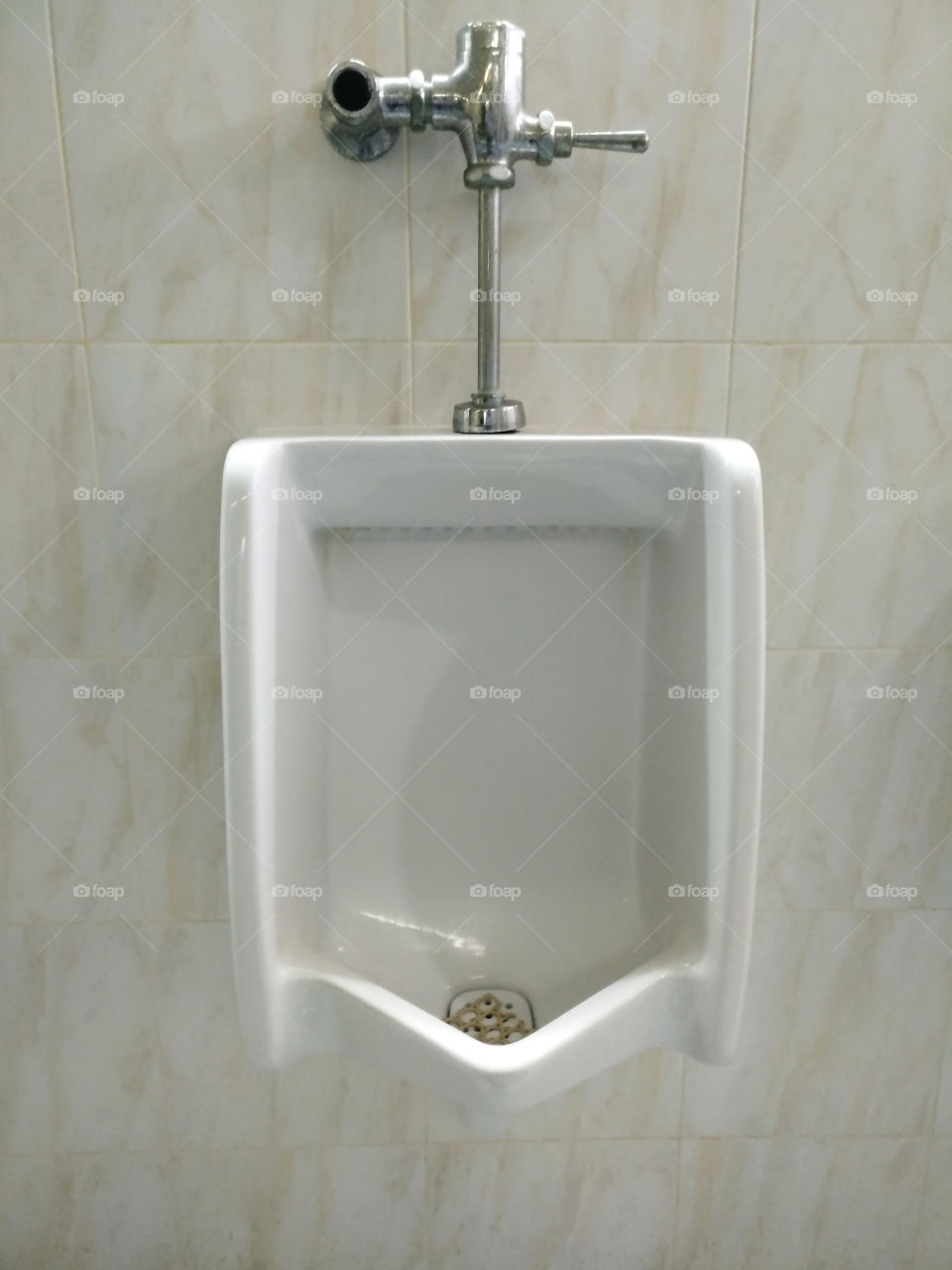 White urinal is mounted in the bathroom.