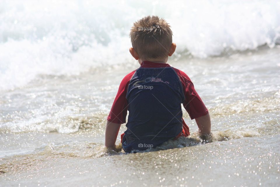 young boy on beach watches waves