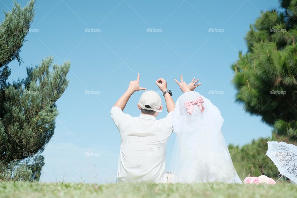loving couple sitting together and doing love sign language using fingers.
