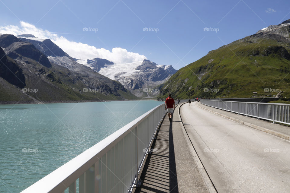 Walking on the dam wall of Stausee Mooserboden high mountain reservoir Austria 