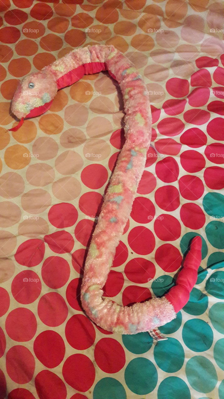 Pink plush snake curled across the bed.