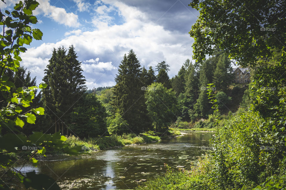 A scenic landscape of a river in a forest in the midst of the Ardennes in Belgium. A great place for hiking in the mountains.