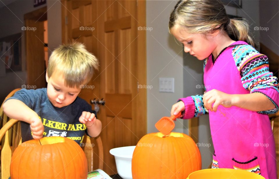 siblings carving pumpkins together