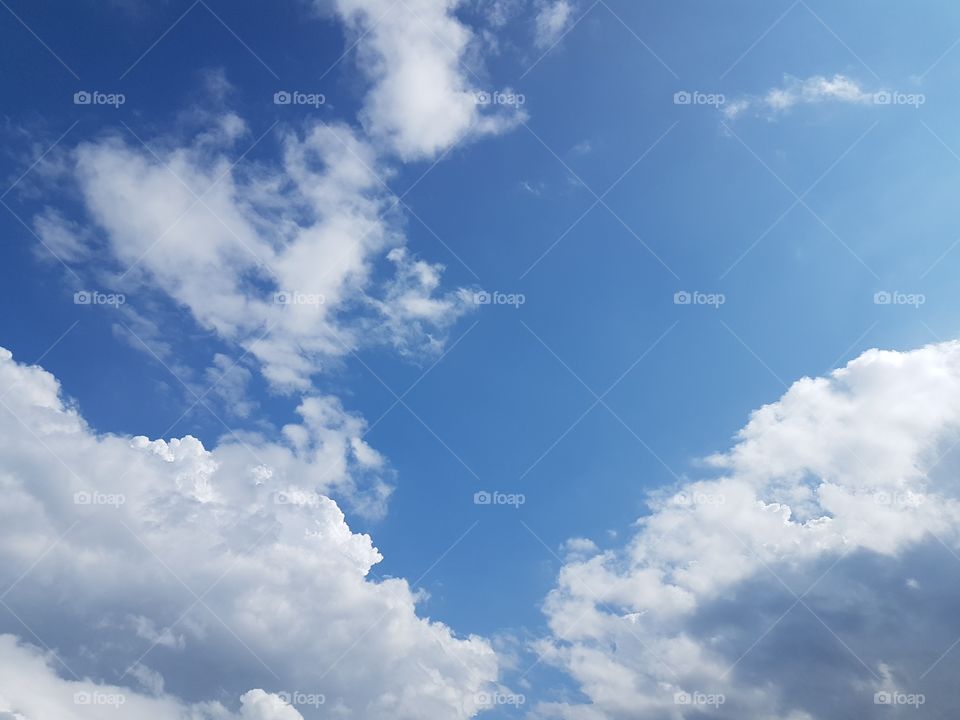 View of white puffy clouds on clear day with blue sky copyspace background