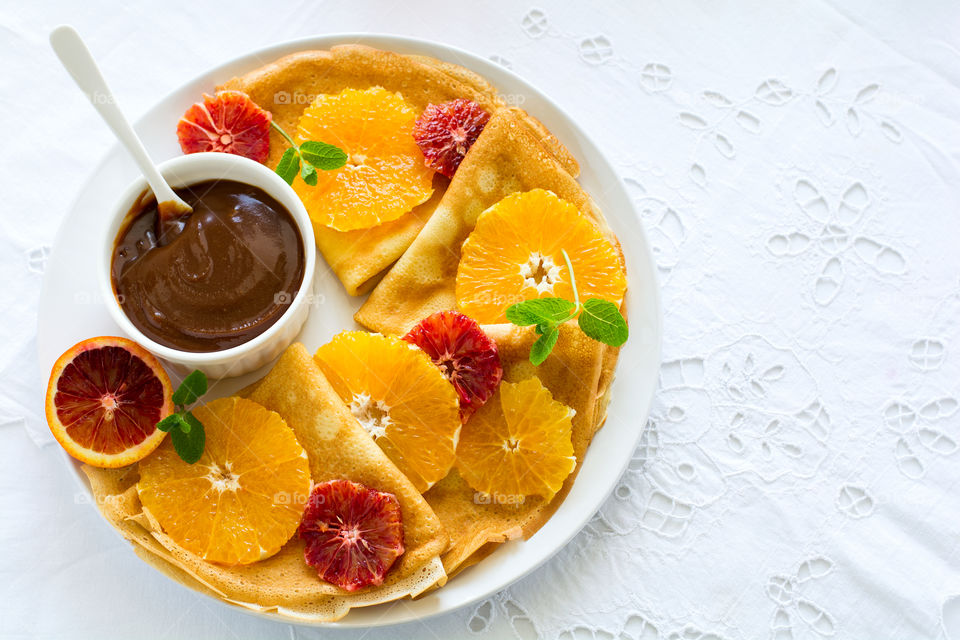 Crepes with oranges, chocolate sauce and nuts