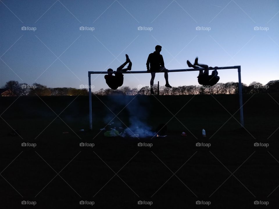 Climbing on a net with a smoky BBQ, silhouetted figures, clear sky