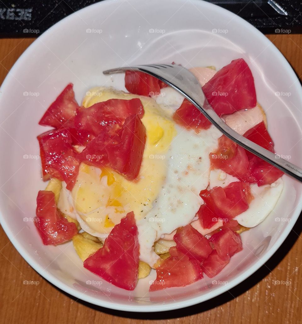 Bowl of fried potatoes with eggs and tomatoes