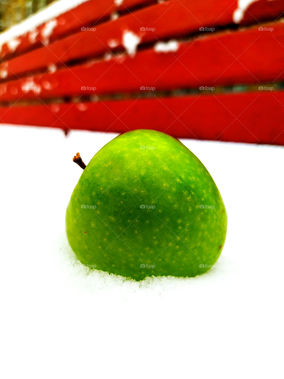 Green apple on a snow-covered bench