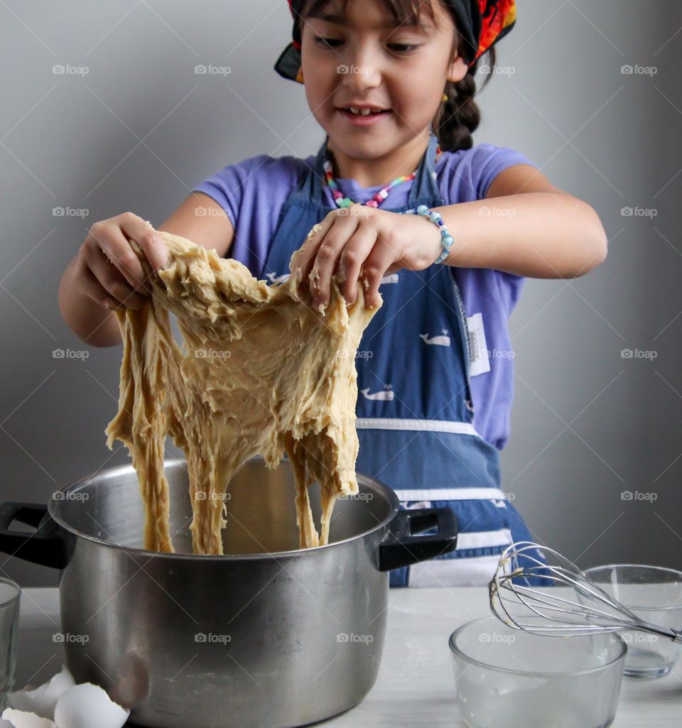 Cute little girl is trying to mix a bread dough