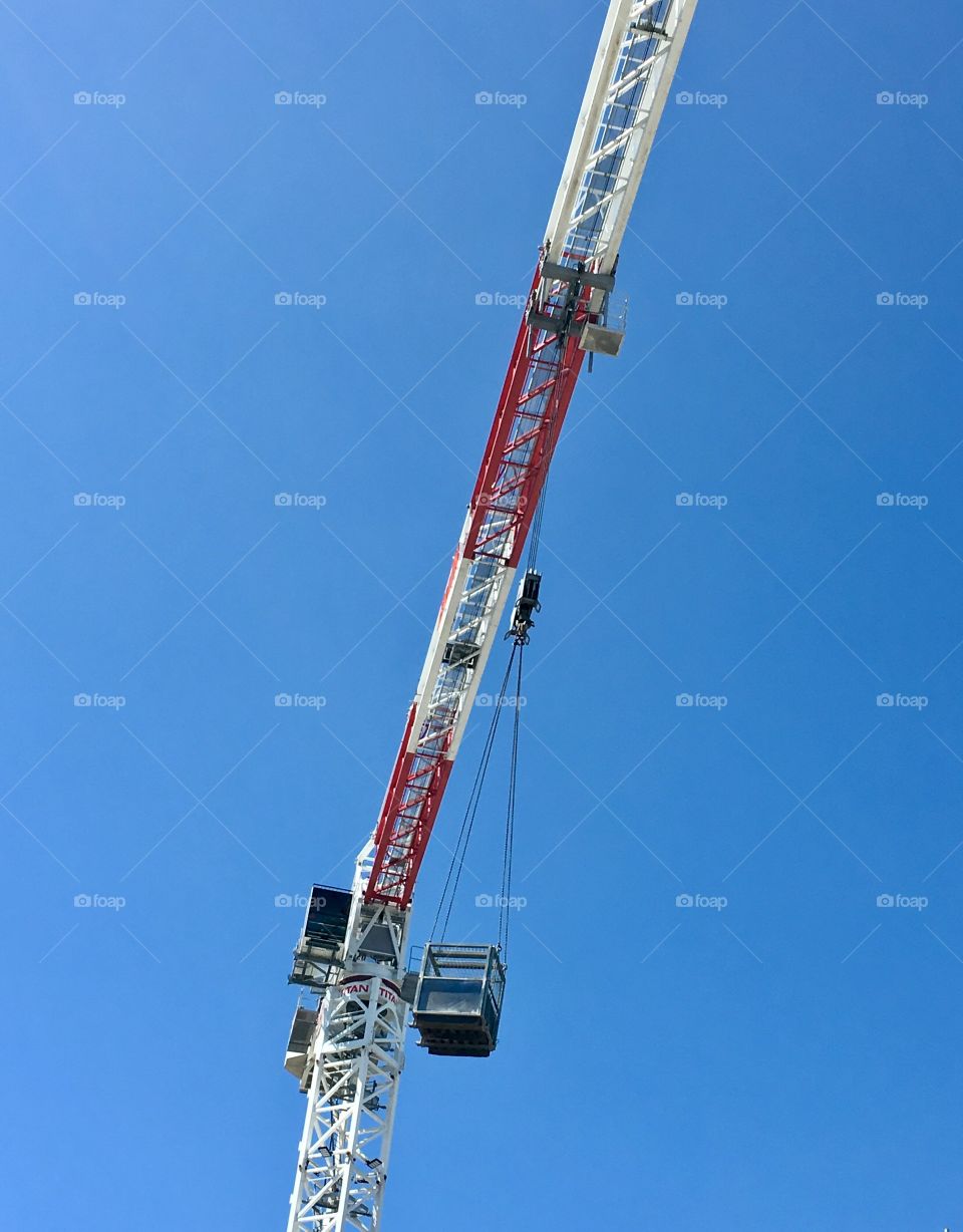 Red and white construction crane with cage against vivid blue sky, desktop minimalistic image 