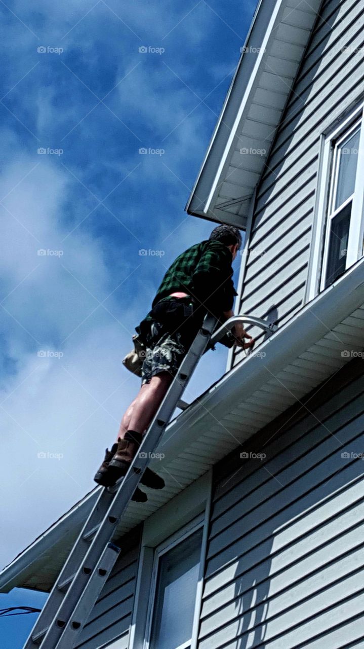 Man on Ladder Replacing Aluminum Siding