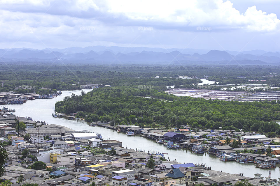 The point of view of Cityscape and a boat parked in Tha Taphao river , Background mountains and sky at Mutsea Mountain Viewpoint in Chumphon , Thailand.