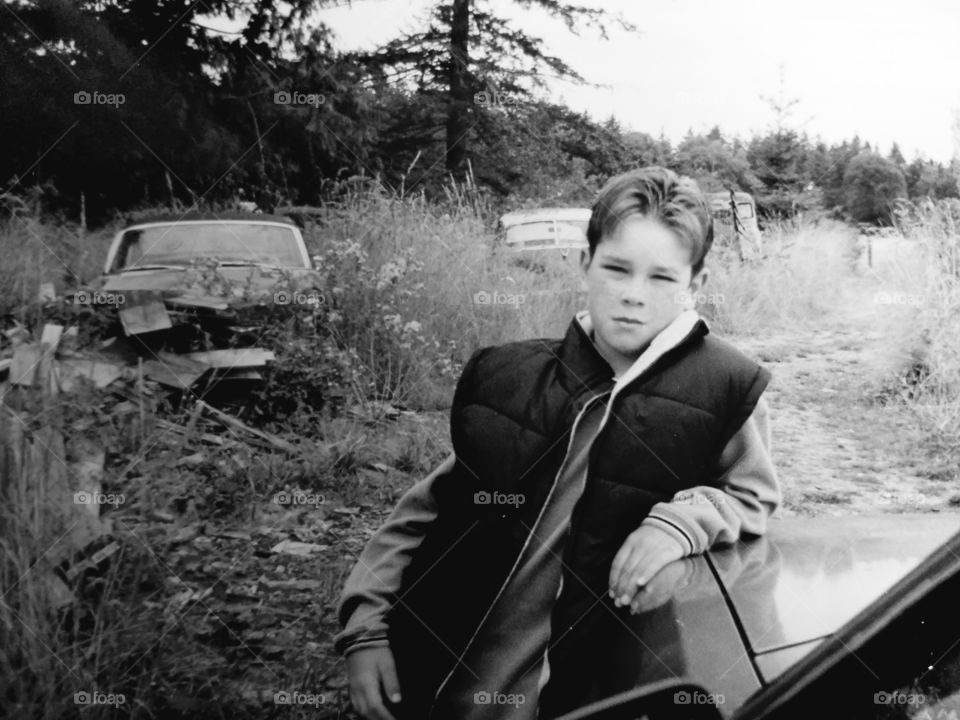 Teenage boy leaning on car