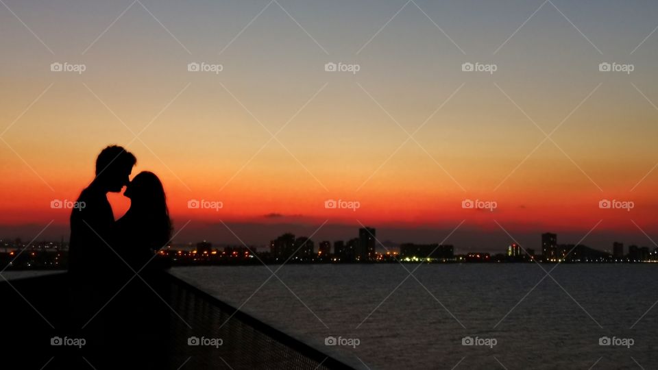 Couple kissing at seascape against sunset