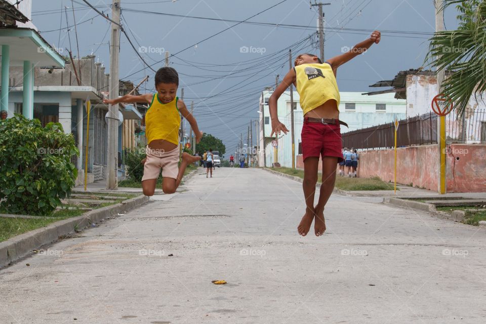 Two Asian boys jumping on road in the town