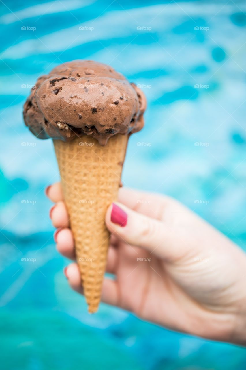 Hand holding chocolate ice cream near beach