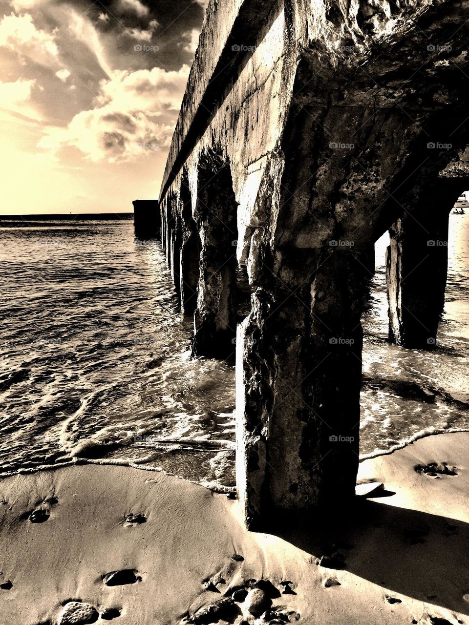 Scene from a beach, sepia beach image, walking along the beach, underneath the pier, walking under the pier 