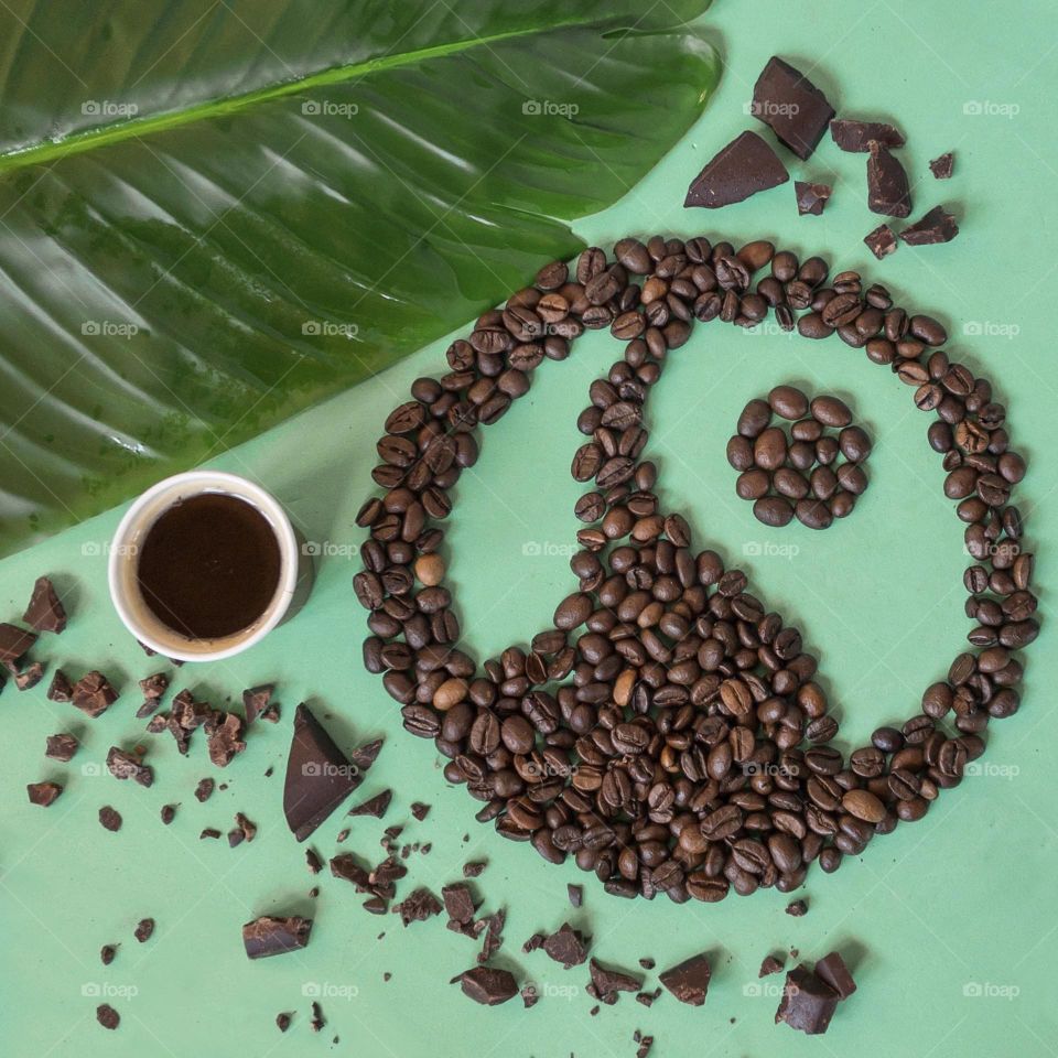 Coffee beans form the Fairtrade logo with chocolate & a banana leaf on a green background 