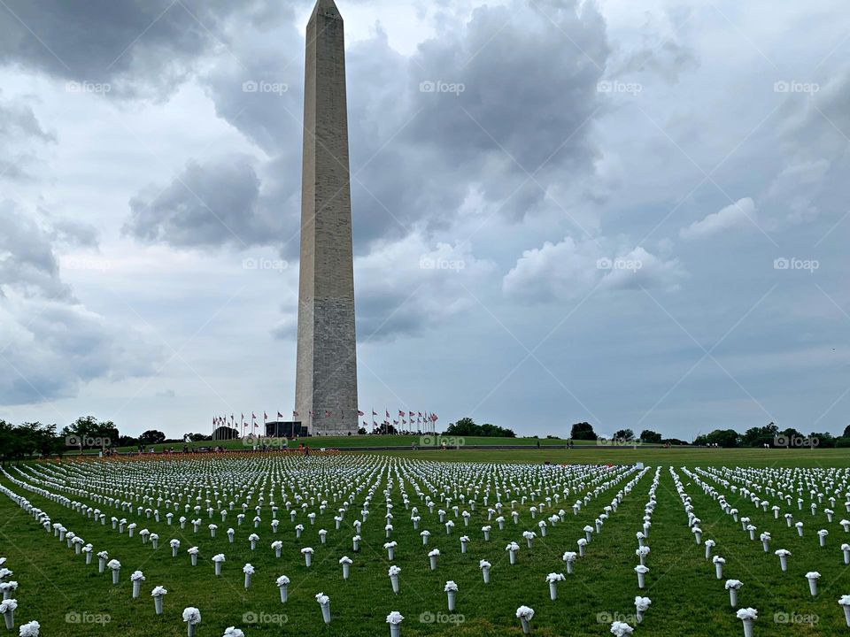 Display markers of the number of Coronavirus victims. The Washington Monument stands day and night as America's tribute to our first President. The fifty American flags that encircle the base of the Monument represent our fifty States