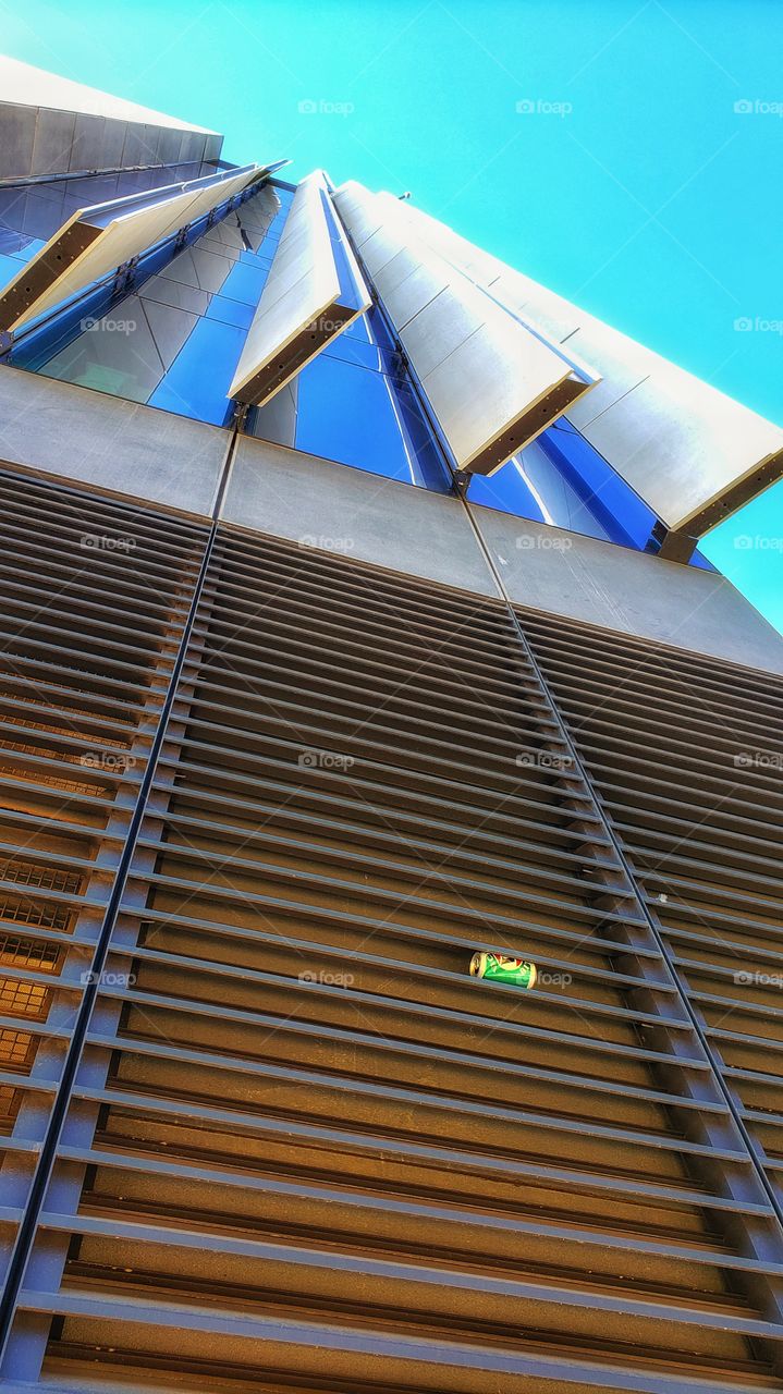 Modern building with an empty beer can wedged in the lower grille. View from street level.