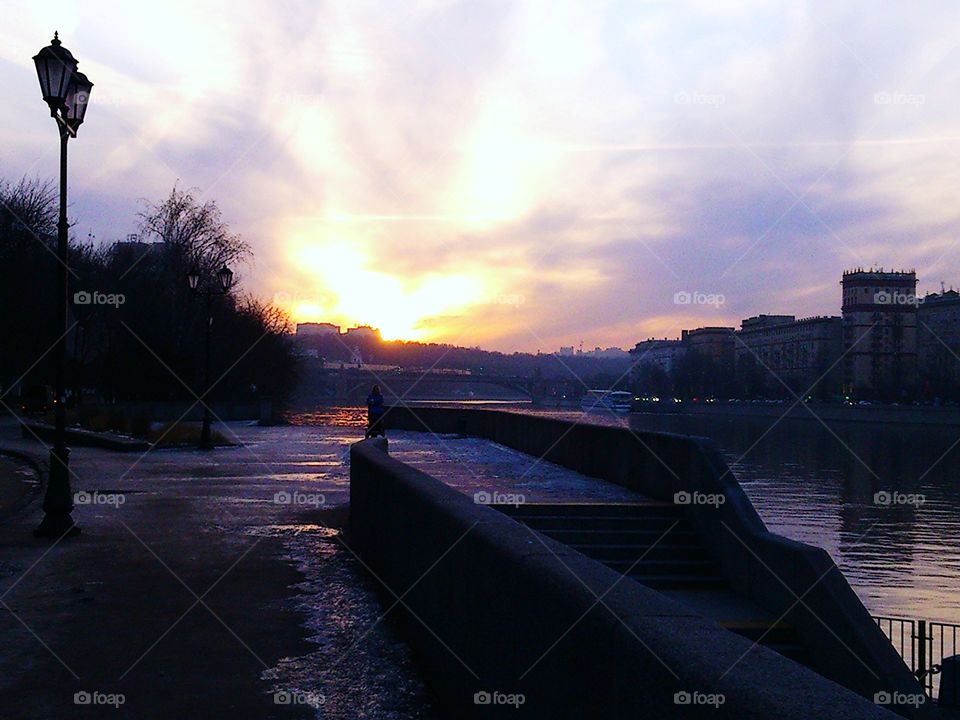 Ice on the pavement on Moscow river embankment, sunset view, tranquil scenery and sky