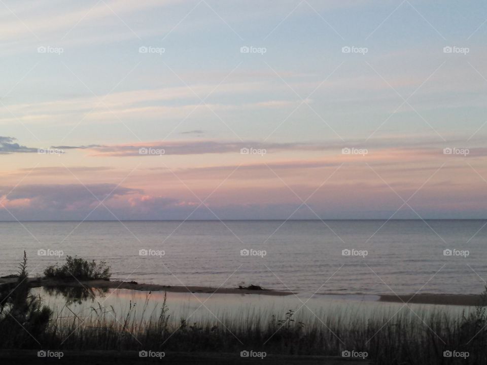 Sunset over water. beautiful sunset over large body of water, sandy beach