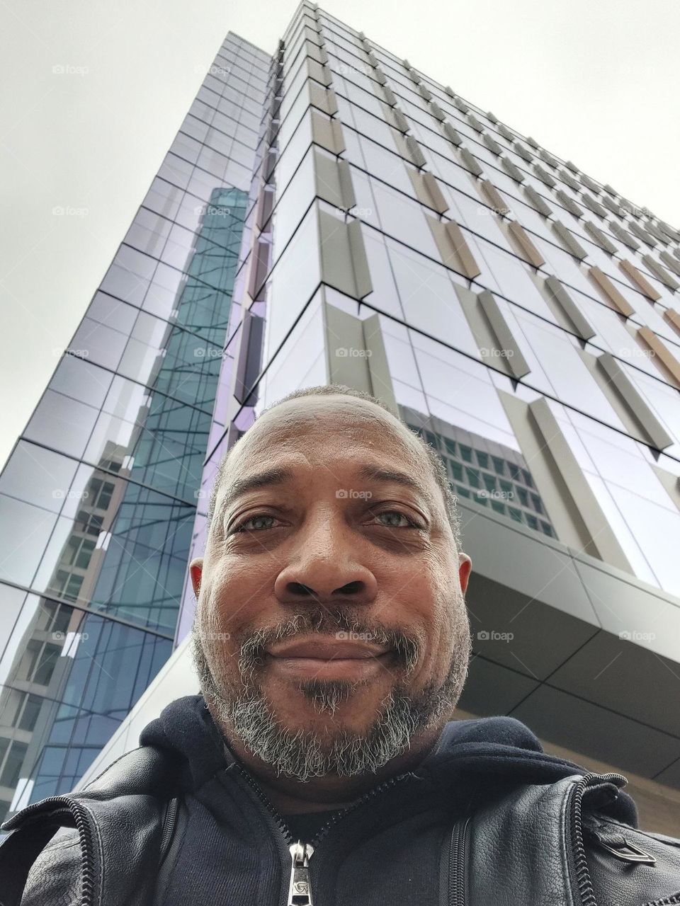 Self-portrait of a photographer with a tall architectural design building in the background