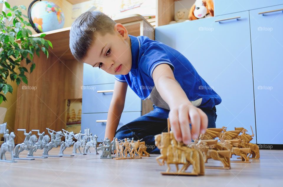 A little boy, a schoolboy, plays with wooden cubes at home, collects a constructor. Toy war.