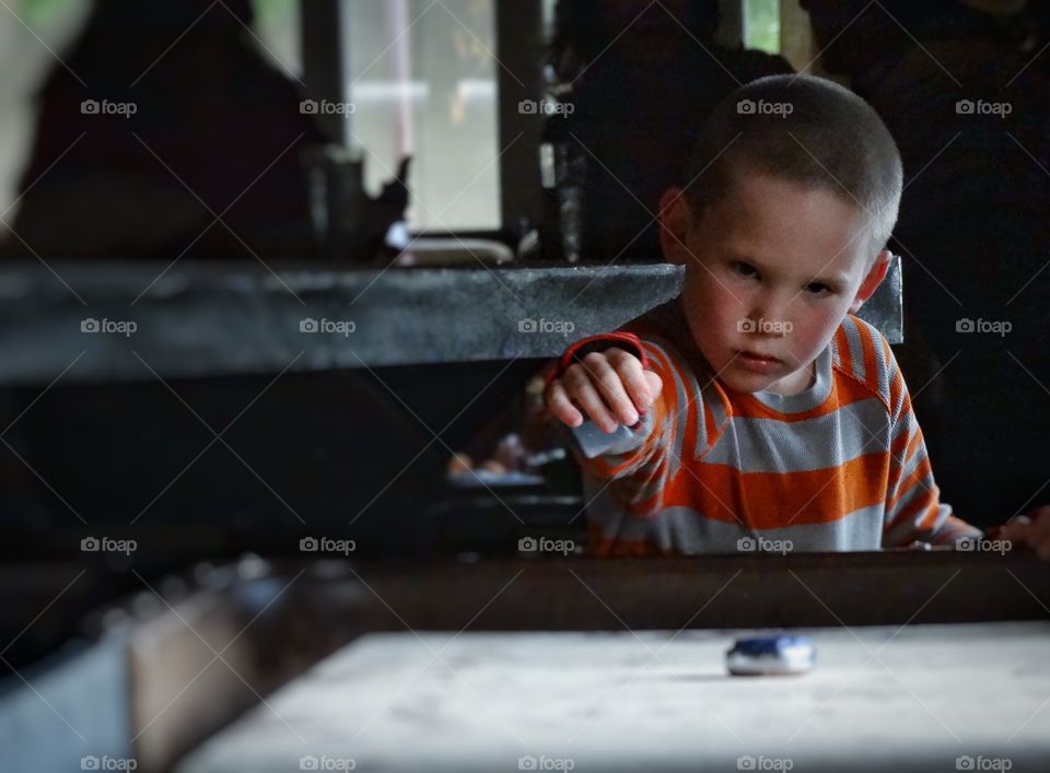 Shuffleboard. Young Boy Playing Indoor Shuffleboard
